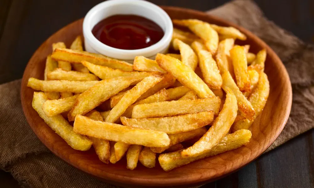 Crispy golden French fries with ketchup in a wooden bowl at Mingxia Dumpling, a Chinese Restaurant in Cordova
